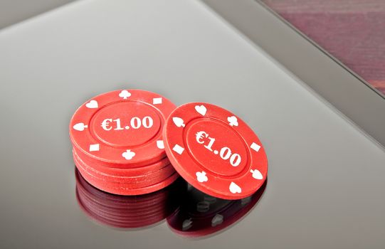 gambling chips on digital tablet pc on old wood table, concept of texas game online