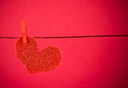 decorative red heart hanging on red background with space for text, concept of valentine day