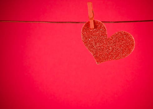 decorative red heart hanging on red background with space for text, concept of valentine day