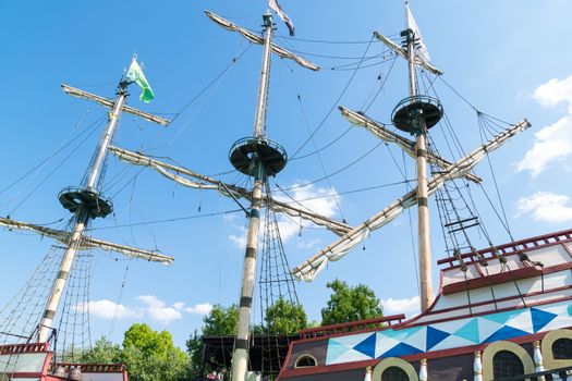 The three masts of a sailboat with furled sails.