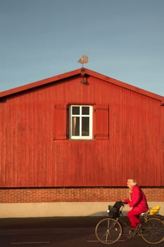 wood  traditional house   in denmark in fanoe im summer, woman on bike passing by