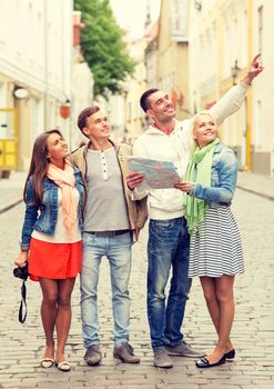 travel, vacation, technology and friendship concept - group of smiling friends with map and photocamera exploring city