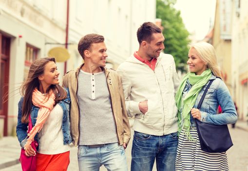 friendship, travel and vacation concept - group of smiling friends walking in the city