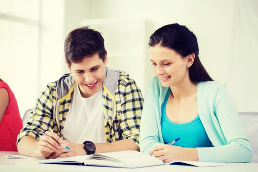 education and school concept - two smiling students with textbooks and books at school