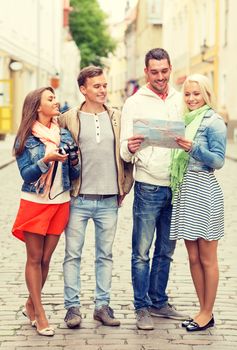 travel, vacation, technology and friendship concept - group of smiling friends with map and photocamera exploring city