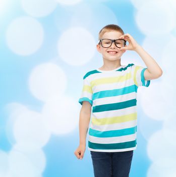 vision, education and school concept - smiling little boy in eyeglasses over blue background