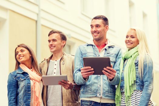 travel, vacation, technology and friendship concept - group of smiling friends with tablet pc computers in the city