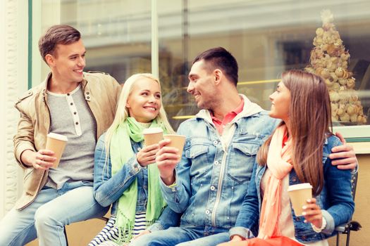 friendship, travel, drink and vacation concept - group of smiling friends with take away coffee