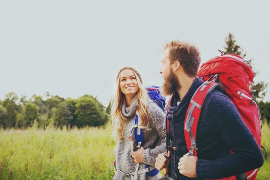 adventure, travel, tourism, hike and people concept - smiling couple walking with backpacks outdoors