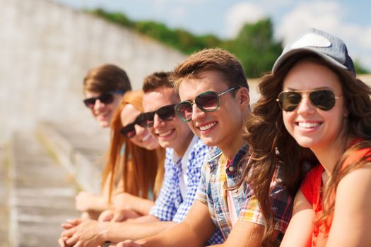 friendship, leisure, summer and people concept - close up of smiling friends sitting on city street