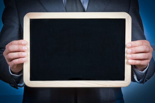 businessman holds a blank blackboard with the hands on a blue background
