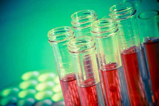 test tubes with red liquid in laboratory on green and yellow light tint background