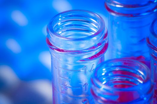 closeup of test tubes with red liquid in laboratory on blue light tint background