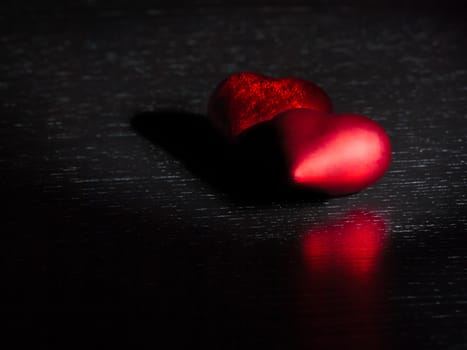two decorative red hearts on black dark light and on wood table with space for text, concept of valentine day