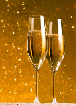 a pair of flutes of champagne on golden bokeh background on table