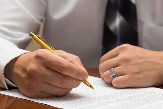 The photo depicts a man signs a document