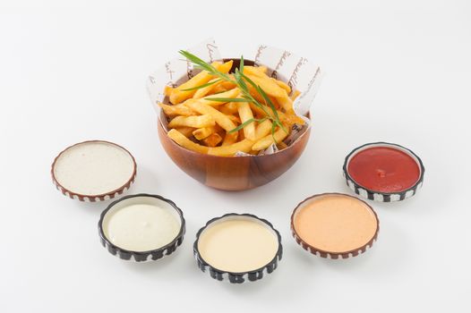 French fries in wood bowl garnished with Japanese bamboo leaves with 5 sauce tartar sauce, wasabi mayo sauce, mayonnaise, thousand island sauce, and ketchup