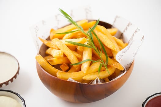 French fries in wood bowl garnished with Japanese bamboo leaves isolated on white background