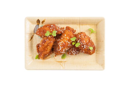 Korean fusion style deep fried chicken wings seasoned with Korean spicy kimchi sauce on square ceramic dish