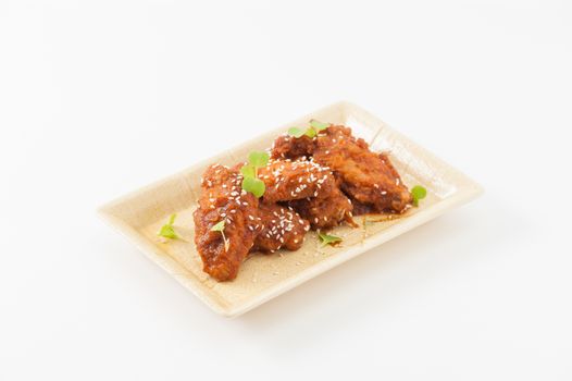 Korean fusion style deep fried chicken wings seasoned with Korean spicy kimchi sauce on square ceramic dish