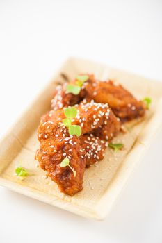 Korean fusion style deep fried chicken wings seasoned with Korean spicy kimchi sauce on square ceramic dish