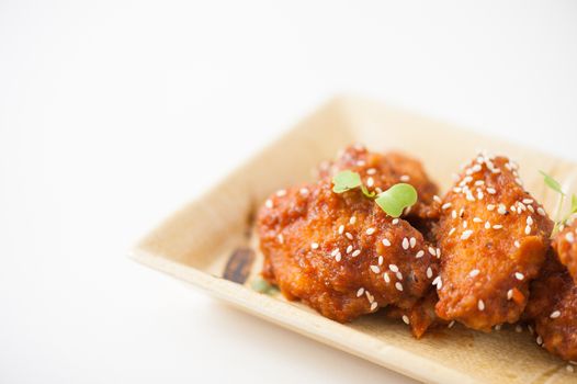 Korean fusion style deep fried chicken wings seasoned with Korean spicy kimchi sauce on square ceramic dish