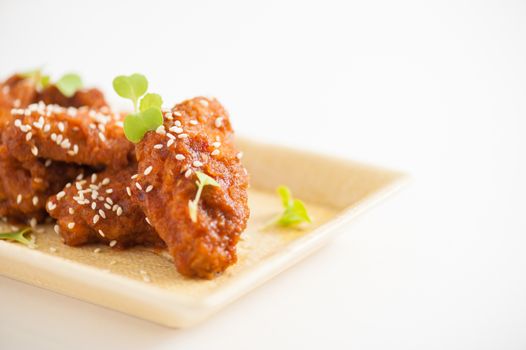 Korean fusion style deep fried chicken wings seasoned with Korean spicy kimchi sauce on square ceramic dish