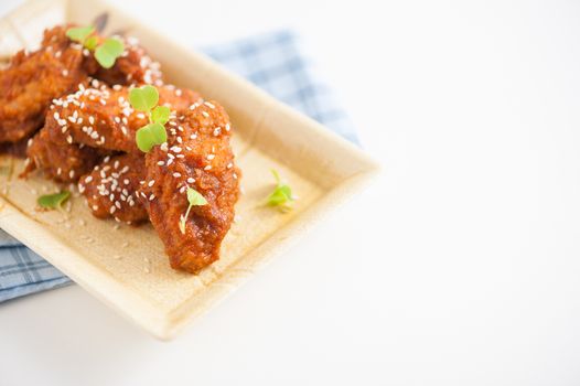 Korean fusion style deep fried chicken wings seasoned with Korean spicy kimchi sauce on square ceramic dish