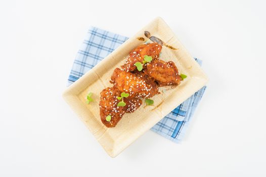 Korean fusion style deep fried chicken wings seasoned with Korean spicy kimchi sauce on square ceramic dish