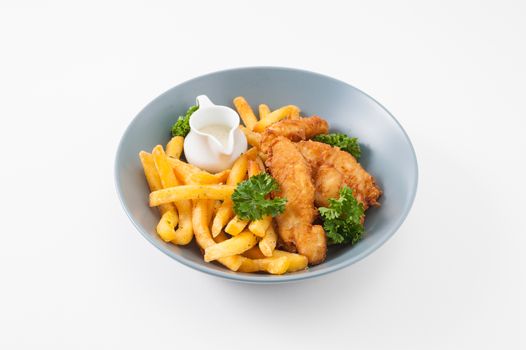 Fried Fish, french fries and tartar sauce garnished with parsley in grey dish
