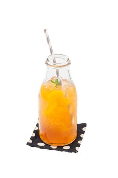 Iced peach tea garnished with mint leaves in glass bottle with striped straw isolated on white background