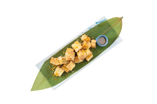 Fake fried tofu (using eggplant replace to tofu) on Japanese bamboo leaf with small cup of plum sauce isolated on white background with clipping path