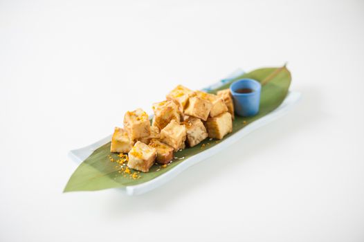 Fake fried tofu (using eggplant replace to tofu) on Japanese bamboo leaf with small cup of plum sauce