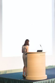 Business woman making business presentation. Female speaker giving a talk at  business conference . Business and Entrepreneurship concept. Brand copy space on white screen.