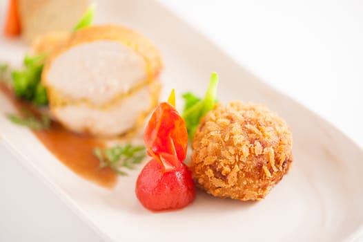 3 modern cuisine Prosciutto Wrapped Chicken with resotto and tamarind sauce, Fried mussaman curry, and Thai chicken spicy sausage on ceramic dish garnished with vegetables, focus on fried curry