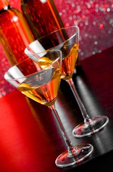 glasses of cocktail on bar table in front of bottles on red tint light bokeh background