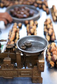 Roast chestnut sale. Closeup of vintage scales near roasted chestnuts on stall