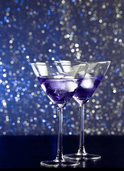 glasses of fresh cocktail with ice on blue tint light bokeh background on bar table