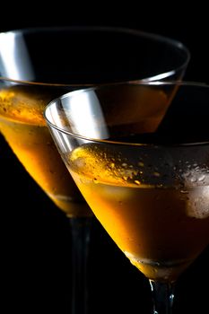 a pair of glasses of fresh cocktail with ice on black background