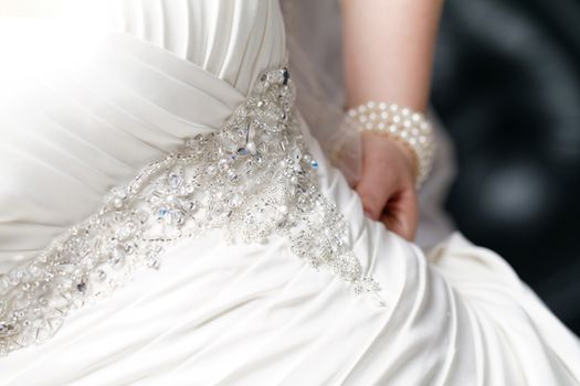 Close up photo of the bride hand in her dress