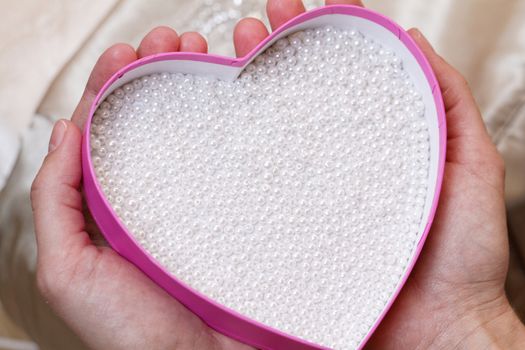 Photo of white pearl in a pink heart-shaped box