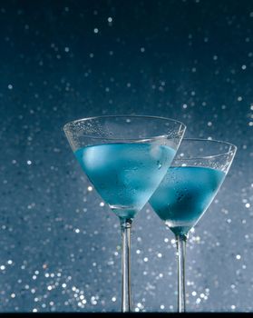 view from below of glasses of fresh cocktail with ice on blue tint light background on bar table