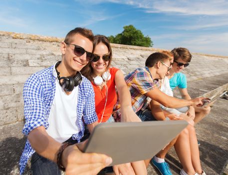 friendship, leisure, summer and people concept - group of smiling friends with tablet pc computers sitting outdoors