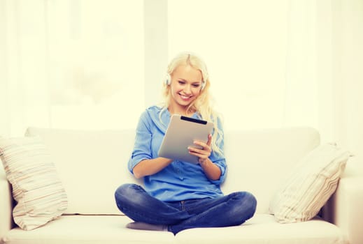 home, music, technology and internet concept - smiling woman lying on the couch with tablet pc computer and headphones at home