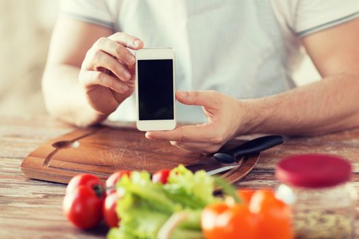 cooking, technology, advertising and home concept - close up of male hands holding smartphone with blank black screen