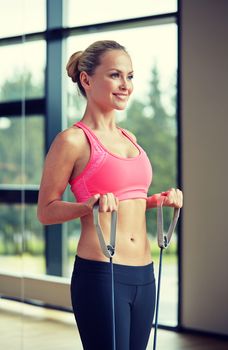 fitness, sport, people and lifestyle concept - smiling woman doing exercises with expander in gym