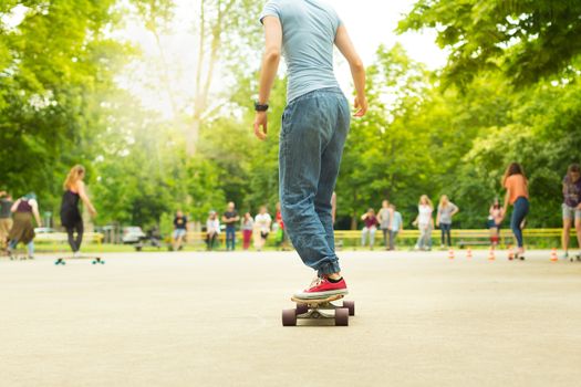 Teenage girl wearing blue jeans and sneakers practicing long board riding in skateboarding park. Active urban life. Urban subculture.