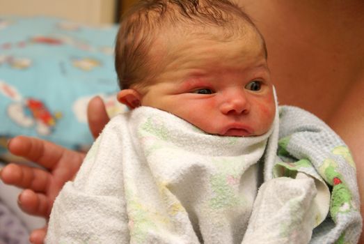 Mom burps her newborn baby boy of less than a week old by patting his back to get the air bubbles out.