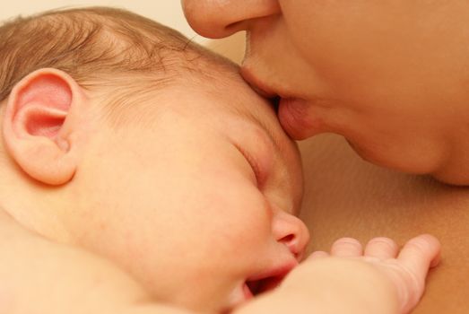 Mom kisses her newborn son on the forehead.