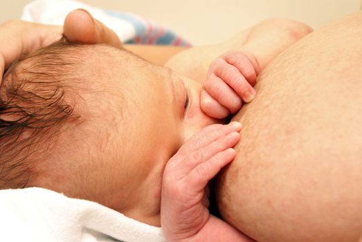 A mother breastfeeds her newborn baby boy of less than a week old.
